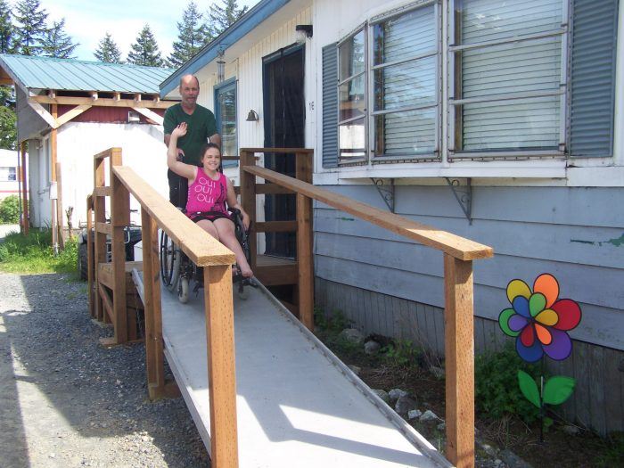 photo of woman using a wheel chair waiving and decending a ramp